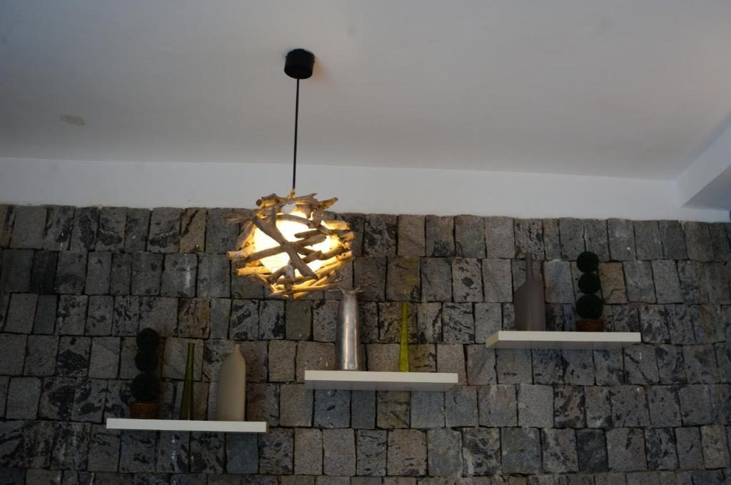 Salon : mur en pierre, étagères flottantes décorées et suspension en bois flotté