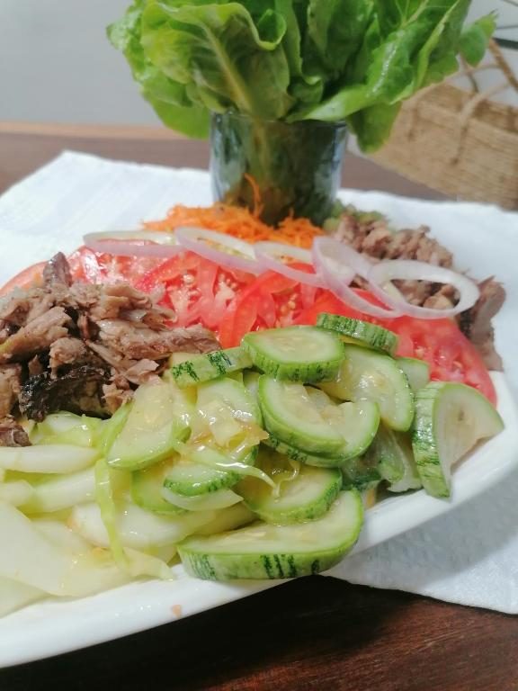 Assiette de crudités : concombre, tomates, oignons, carottes râpées et viande effilochée, avec un bouquet de salade